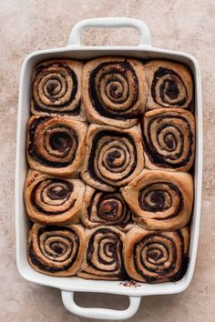 a white casserole dish filled with cinnamon rolls