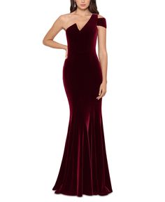 a woman wearing a long velvet dress with an open shoulder and slited skirt,