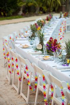 a long table set up with pineapples and flowers on it for a party