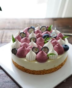 a white plate topped with a cake covered in blueberries and cucumber slices