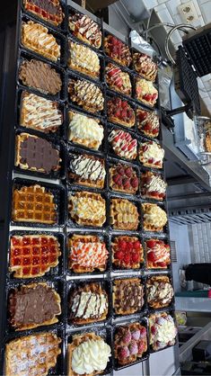 many different types of waffles and other pastries are arranged in trays