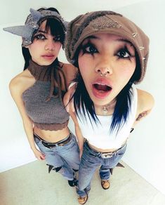 two young women standing next to each other in front of a white wall with their mouths open