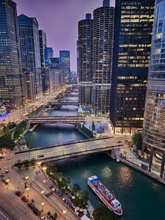 a boat traveling down a river next to tall buildings in a large city at night