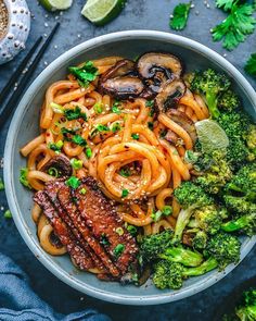 a bowl filled with noodles, broccoli and mushrooms