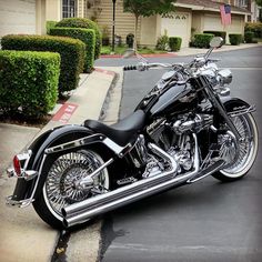 a black and chrome motorcycle parked on the side of a road next to a house