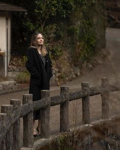 a woman is standing on a wooden fence