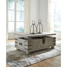 a coffee table with two candle holders on it in front of a window and rug