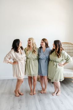 three women in robes standing next to each other on a wooden floor with white walls