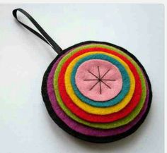 a multicolored round ornament hanging from a black cord on a white surface