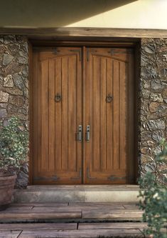 two wooden doors in front of a stone building with potted plants on the steps