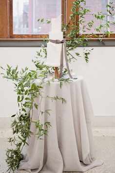 a table topped with a cake covered in greenery