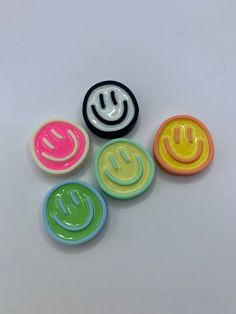 four different colored smiley face magnets on a white surface