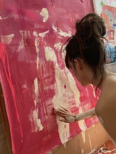 a woman is painting with pink and white paint