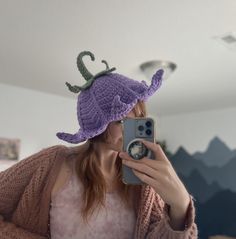 a woman taking a selfie with her phone wearing a crocheted dragon hat