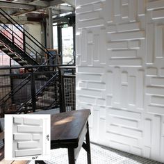 a wooden table sitting in front of a wall with white tiles on it and stairs