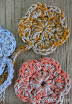 three crocheted coasters sitting on top of a wooden table