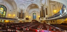 the inside of a church with pews and stained glass windows on the ceiling,