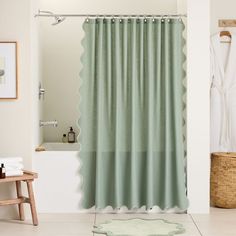 a bathroom with a green shower curtain next to a white bath tub and wooden stool