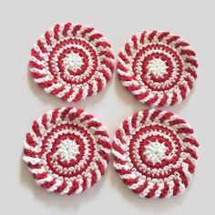 four red and white crocheted coasters sitting next to each other