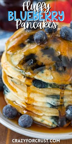 blueberry pancakes are stacked on top of each other with syrup drizzled over them