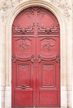 a large red door with ornate carvings on it's sides and an arched doorway