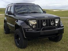 a black jeep parked on top of a lush green field