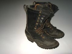 an old pair of black boots sitting on top of a white table next to each other