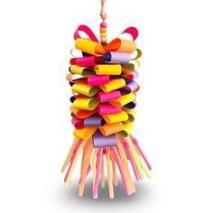 a colorful toy hanging from a string on top of a white wall with an orange stick sticking out of it's center