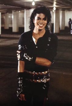 michael jackson standing in an empty parking garage with his arms crossed and smiling at the camera