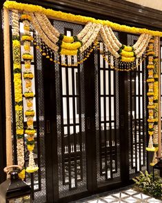 the entrance to a building decorated in yellow and white garlands with hanging lights on each side