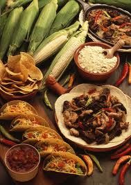 an assortment of mexican food on a table with corn, tortillas and beans