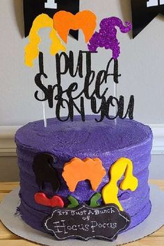 there is a purple cake with black letters and decorations on top that say i put a spell on it