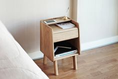 a bedside table with magazines on it next to a bed