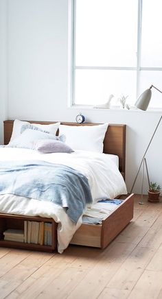 a bed sitting on top of a hard wood floor next to a window with lots of light