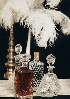 an assortment of perfume bottles sitting on a table next to a white feathery tree