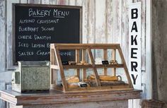 an old bakery display with bread and pastries on the counter in front of a chalkboard