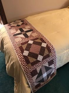 a bed with a quilt on top of it in a room next to a wall