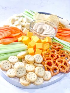 a platter filled with crackers, pretzels, carrots and cheese