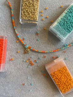 there are some beads in plastic containers on the floor next to a beaded necklace