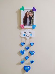 a photo frame hanging from the side of a wall with hearts and clouds attached to it