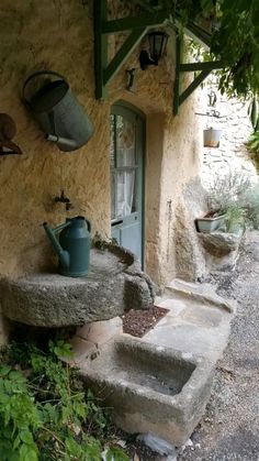 an old stone house with steps leading up to the front door and potted plants