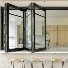 three stools are sitting in front of an open kitchen with glass doors on the wall