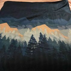 a blanket with mountains and trees painted on it