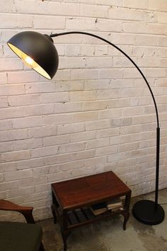 a lamp that is next to a table with a book on it and a chair