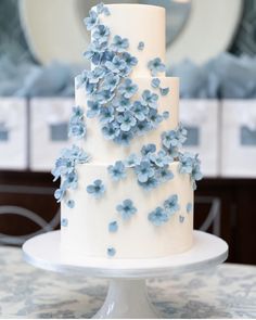 a three layer white cake with blue flowers on it