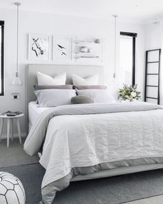 a white bedroom with lots of windows and decor on the walls, along with a large bed