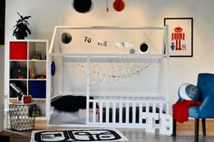 a white bunk bed sitting in a bedroom next to a blue chair and bookshelf