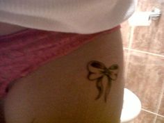 a woman with a bow tattoo on her lower back leg and the bottom half of her stomach