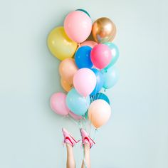 a woman is holding many balloons in her hands while sitting on the floor with her feet up