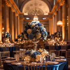 a tall centerpiece with blue and white flowers sits on top of a round table